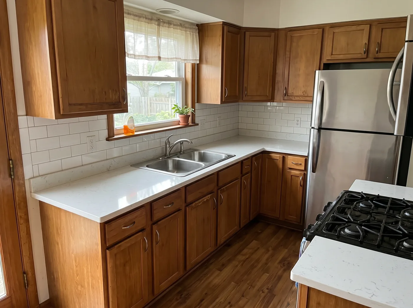 A rehabilitated unit kitchen after a make-ready, with clean light counters, a tidy sink and a clear, move-in-ready finish