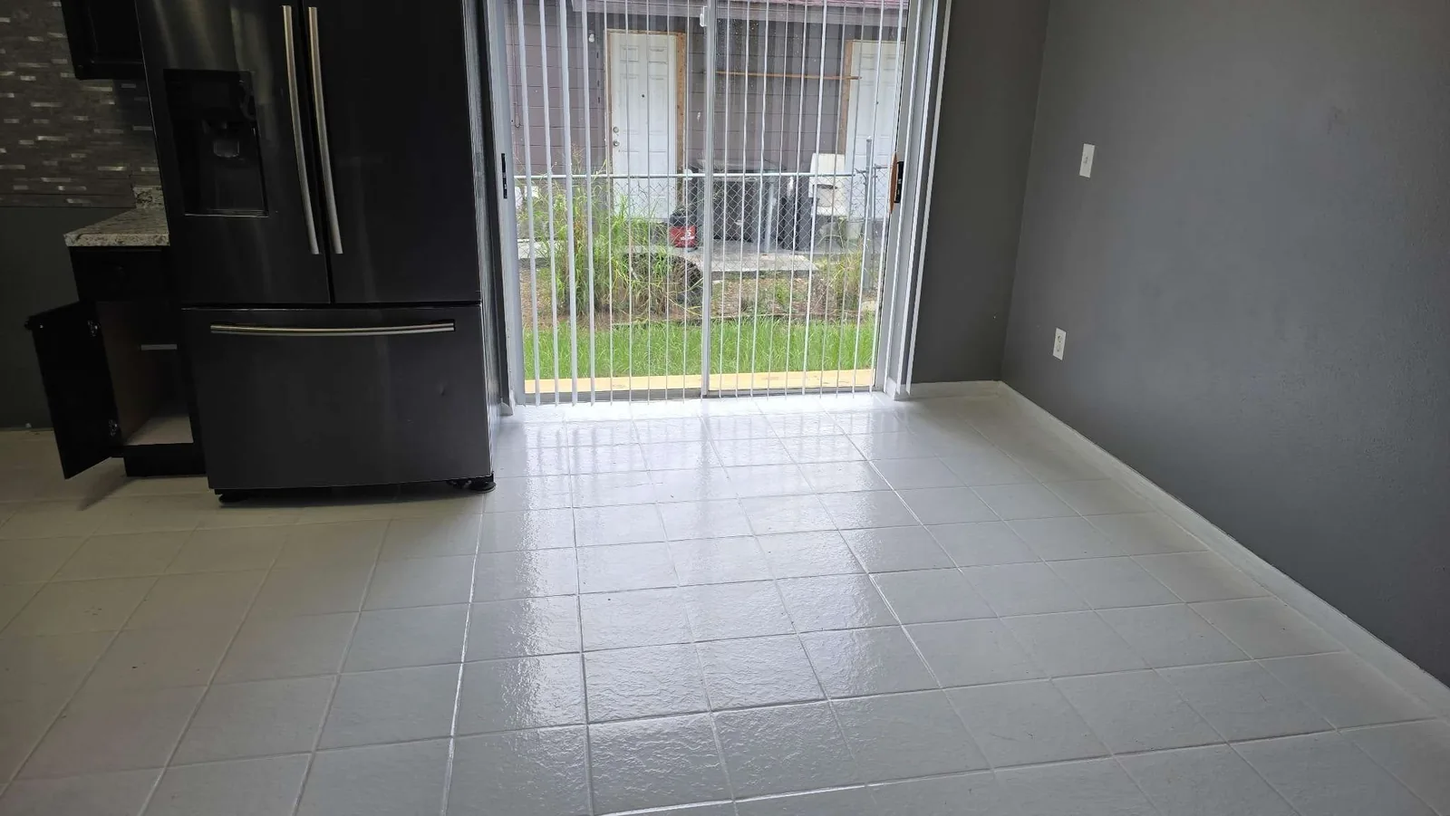 A refinished, glossy white tile floor and clean, open dining area after the rehab