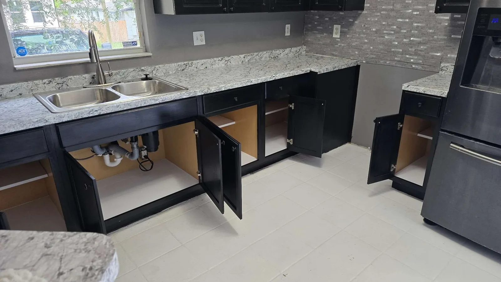 The same under-sink cabinet rebuilt with clean plumbing and fresh shelf liners after the rehabilitation